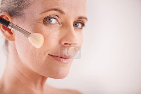Photo for Brush, beauty and portrait of woman in studio for cosmetic, self care and facial glow routine. Makeup, foundation and mature person with cosmetology tool for treatment by white background with mockup. - Royalty Free Image