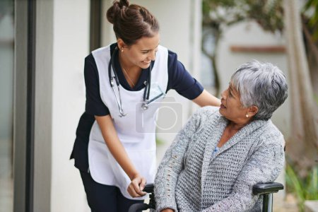 Photo for Senior woman and wheelchair at nursing home with carer for assistance in closeup, help at clinic. Disabled retiree and medical or outdoors for talk or plan for healthcare, conversation with nurse. - Royalty Free Image