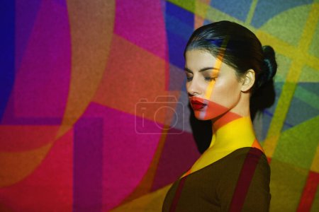 Photo for Surreal, abstract and face of woman by color, art and pattern of shapes serious for creative career. Light, female person and lady by wall with skin for cosmetics, beauty and makeup or treatment. - Royalty Free Image