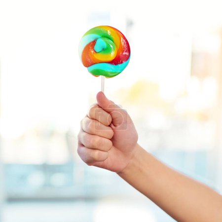 Photo for Hand, lollipop and candy for kid, home and mockup for sugar, show and promotion for sweets for snack. House, growth and development of child, dessert and unhealthy food, spiral and color of treat. - Royalty Free Image