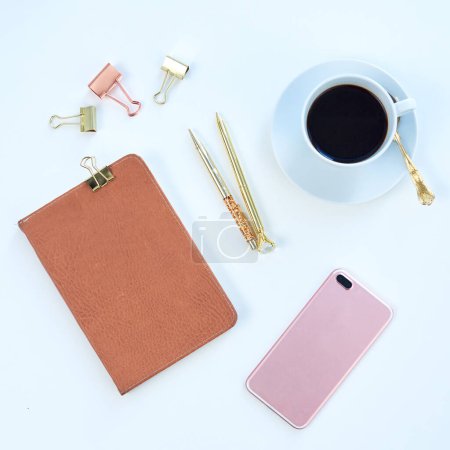 Photo for Above of notebook, phone and coffee in studio for working, writing notes and planning for career. Creative desk, business and diary, smartphone and stationery for social media on blue background. - Royalty Free Image