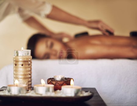 Candles, hot stones and wax light at a spa for lomi lomi massage, healing or luxury treatment therapy. Health, aromatherapy and wellness products for calm, zen or peaceful atmosphere at natural salon.
