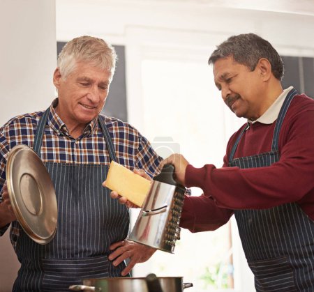 Senior, lernen und kochen mit Käse für Topf oder Nudelgericht in der Küche zusammen im Altenheim. Männliche Person, Freunde oder Team in der Gastfreundschaft mit Zutaten, Schürze oder Rezept im Haus.