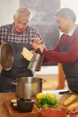 Photo for Senior man, teaching and cooking with pot for cheese or diary dish in kitchen together at old age home. Male person or team learning in hospitality with mixing ingredients, food or recipe at house. - Royalty Free Image