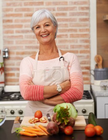 Photo for Senior woman or arms with knife in kitchen or confident, tomato or carrots for diet. Female chef in portrait with healthy vegetables for nutrition, peeling green lettuce with onion in retirement home. - Royalty Free Image
