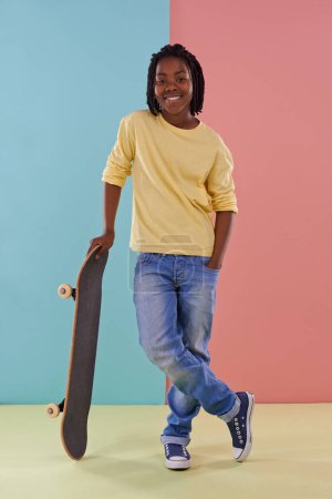 Téléchargez les photos : Enfant, skateboard et portrait pour la mode, colorblock et skate pour adolescent, cool et ludique pour le plaisir. Garçon africain ou entre et sourire avec jouet pour actif, jeune et à la mode pour l'enfance et les enfants. - en image libre de droit