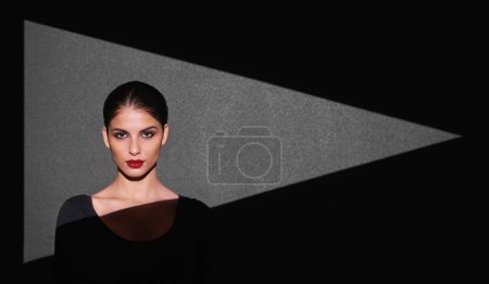Photo for Portrait, abstract and woman with light of triangle, shape and isolated on gray background. Female person, lady and spotlight on face for cosmetics, beauty and makeup by mockup on studio backdrop. - Royalty Free Image