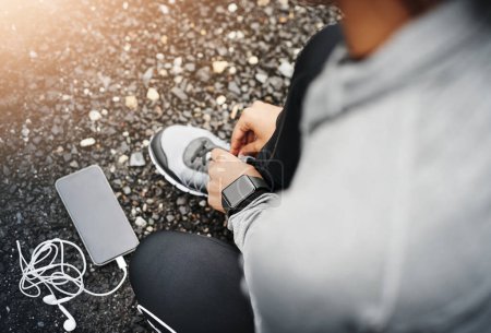 Foto de Person, smartphone and shoelace with running or exercise for fitness, health and wellbeing in outdoor. Above, sneakers and committed on workout or jog in morning for training, wellness and self care. - Imagen libre de derechos
