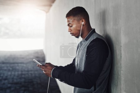 Photo for African athlete, phone and earphones with text, start and workout for training and health. Man, music and cellphone for cardio, sports and wellness with exercise and outdoor summer fitness for runner. - Royalty Free Image