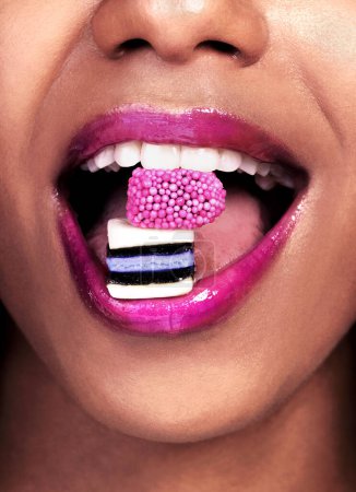 Photo for Eating, closeup and black woman with sweets for nutrition, luxury and abstract isolated on pink background. Mouth, gen z girl with licorice for food, wellness and happy on studio backdrop by mockup. - Royalty Free Image