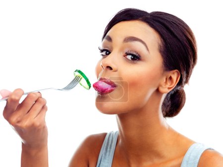 Téléchargez les photos : Portrait, fork and woman with cucumber, nutrition and sustainable eating to lose weight in studio. Vegetable, salad and girl with fresh food for detox diet, vitamins or gut health on white background. - en image libre de droit