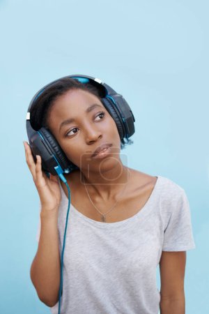 Photo for Thinking, music and black woman with headphones in city for sound, track or listening to podcast on blue background. Streaming, earphones or gen z student outdoor with radio, playlist or audio ebook. - Royalty Free Image