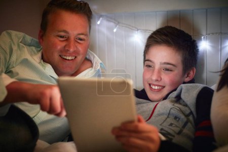 Photo for Home, dad and son with tablet at night for online games, reading ebook story and elearning multimedia. Man, father and happy kid streaming cartoon, movies or digital technology in bedroom for bonding. - Royalty Free Image