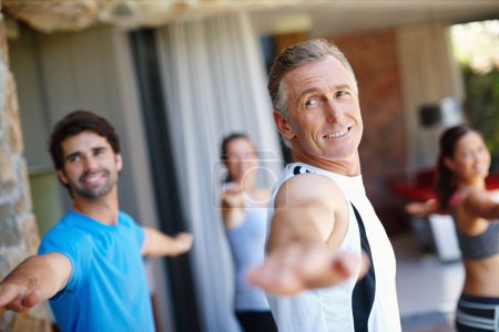 Reifer Mann, posiert und glücklich in Yoga-Kurs für Fitness und geistiges Wohlbefinden, Workout und tägliche Lektion, um Menschen zu coachen. Männliche Yogini, Kriegerhaltung und Yogis oder Studenten üben Kraft und Gleichgewicht