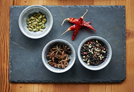 Photo for Chilli, ingredients and spices in bowl above on board for cooking for cuisine, meal and lunch. Condiments, seasoning and dried pepper for gourmet dinner with cardamon seeds, star anise and peppercorn. - Royalty Free Image