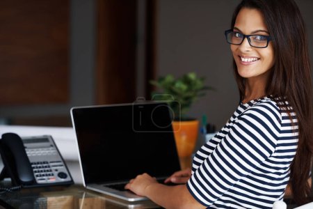 Photo for Portrait, laptop screen and home office with designer woman in workplace for small business or startup. Desk, computer and smile with happy young employee in apartment for creative job or work. - Royalty Free Image