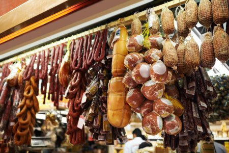 Photo for Hooks, butcher and dry meat in shop for traditional food, groceries or products in Germany. Supermarket, deli and fermented or smoked sausages hanging in row for production in grocery store - Royalty Free Image