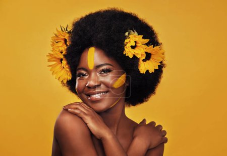 Photo for Black woman, sunflowers in hair and make up on face in studio portrait for cosmetics, afro care and empowerment. Happy, lady and yellow paint on forehead for summer, spring or warmer weather. - Royalty Free Image