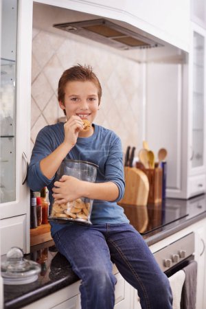 Photo for Portrait, smile and cookie jar with boy child in kitchen of home, eating biscuits on counter in morning. Breakfast, food and relax with happy young kid in apartment for hunger, snack or treats. - Royalty Free Image