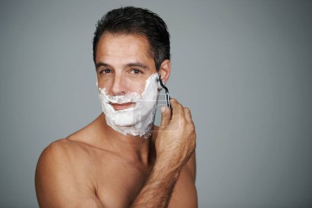Photo for Shaving cream, portrait and man in studio with razor for epilation or hair removal treatment. Skin, natural and face of mature person with shaver for facial dermatology routine by gray background - Royalty Free Image