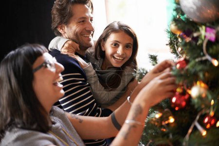 Photo for Parents, child and excited at tree for Christmas decoration, bonding and fun in family home. Festive, xmas decor and mother with girl kid, father and happy holiday for portrait, love and celebration - Royalty Free Image