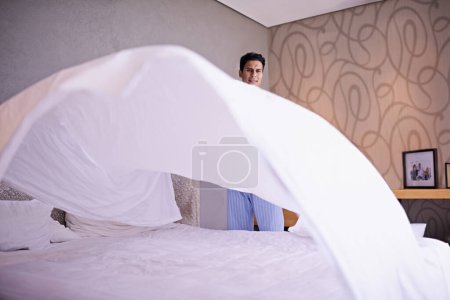 Photo for Man, morning and making bed in home for hygiene and routine of change fresh linen on weekend. Tidy, bedroom or modern guy with happy for housekeeping, healthy or spring cleaning on vacation in house. - Royalty Free Image