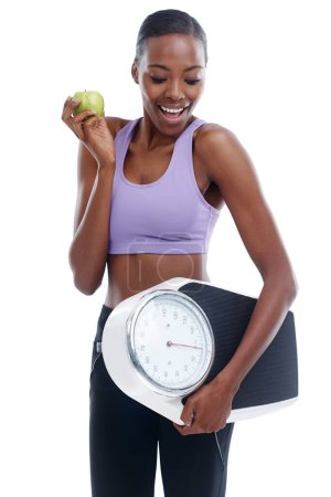 Téléchargez les photos : Fitness, pomme et balance avec une femme noire heureuse en studio isolé sur fond blanc pour la perte de poids. Exercice, sourire et régime alimentaire avec de jeunes sportifs confiants modèle d'entraînement pour la santé ou la nutrition. - en image libre de droit