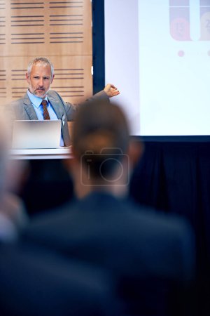 Photo for Senior, businessman and manager with presentation on projector for meeting, seminar or conference at office. Mature man, CEO or speaker talking on podium to group or corporate audience at workshop. - Royalty Free Image
