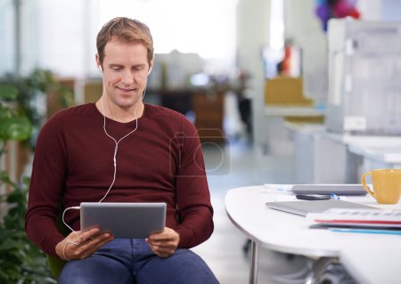 Tablet, relax and businessman with earphones, desk and working in office workplace. Smile, technology and watching business videos or streaming, elearning and internet research for online project.