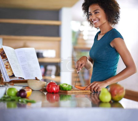 Photo for Cooking, happy woman and cutting vegetables with recipe book in kitchen for healthy diet, nutrition or lunch. Chopping board, food or African person preparing salad for dinner or organic meal in home. - Royalty Free Image