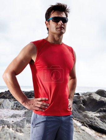 Photo for Athletic man, confident and beach for fitness, health and wellness in activewear and sunglasses. Male person, jog and seaside for sport, train and triathlon in exercise for cardio outdoor routine. - Royalty Free Image