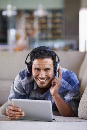 Photo for Man, headphones and tablet for music or website, home and internet for streaming. Happy male person, relax and song app on couch for audio or podcast, smile and online for blog or subscription. - Royalty Free Image