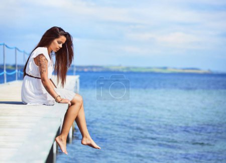 Téléchargez les photos : Femme, assis et l'océan sur le quai en été avec la pensée, la mémoire et se détendre en vacances avec l'espace de maquette. Fille, personne et idée par vagues, mer ou eau par pont, promenade ou quai en vacances en Italie. - en image libre de droit