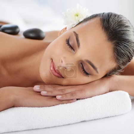 Photo for Zen, hot stone and woman with massage at spa for wellness, health and back treatment. Self care, cosmetic and young female person sleeping for warm rock skin therapy at natural beauty salon - Royalty Free Image