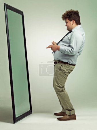 Photo for Man, mirror and plus size with reflection for confidence in body fat, fashion or outfit on a studio background. Young male person or big model in obesity, overweight or challenge on mockup space. - Royalty Free Image