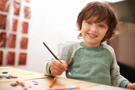 Téléchargez les photos : Garçon heureux, portrait et dessin en couleur pour la créativité, l'apprentissage ou l'éducation à la maison. Jeune enfant avec sourire et crayon pour dessiner, écrire ou travailler dans le développement de la petite enfance à la maison. - en image libre de droit