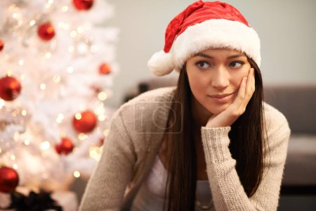 Photo for Christmas, face and thinking with bored woman in living room of home for memory or nostalgia. Planning, idea or sad and lonely young person with Santa hat in apartment for December holiday season. - Royalty Free Image