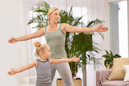 Téléchargez les photos : Yoga, exercice avec maman et fille dans le salon, étirant les bras pour l'équilibre et la liaison. Femme, jeune fille et fitness ensemble à la maison familiale, santé et bien-être avec amour et soin. - en image libre de droit