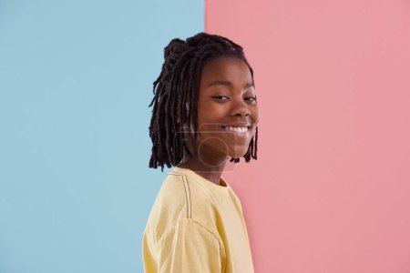 Photo for Happy teenager, portrait and fashion in studio with creative color, style and blue and pink background. Face of young and cool African model or boy in natural hair and casual clothes with pastel. - Royalty Free Image