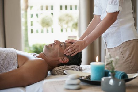 Photo for Relax, head massage and man at spa for skincare, peace and calm at luxury resort at table for wellness. Beauty, therapy and person at salon for face treatment, health and hands of masseuse pampering. - Royalty Free Image
