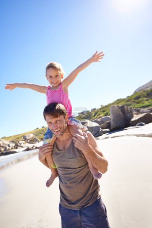 Foto de Retrato, hombre y chica al hombro para jugar, vacaciones y vinculación en la playa de Nueva Zelanda. Padre, llevar o hija de vacaciones, felicidad o la luz del sol para la diversión, la familia o el juego en el día de verano. - Imagen libre de derechos
