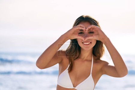 Photo for Heart, hands and portrait of woman at beach for summer holiday, island trip and adventure in Bali. Happy, emoji and relax by ocean with love for tourism, weekend travel and finger shape on vacation. - Royalty Free Image