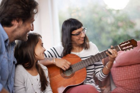 Photo for Woman, music and playing guitar for family at home, relaxing and enjoying together on couch. Performance, father and child with mother in living room, entertainment and happy with musical instrument. - Royalty Free Image