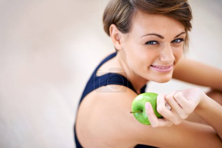 Portrait, exercise and happy woman with apple in gym for diet, nutrition or wellness with healthy body. Face, fitness and person eating fruit for vitamin c or benefits of organic food on mockup space.