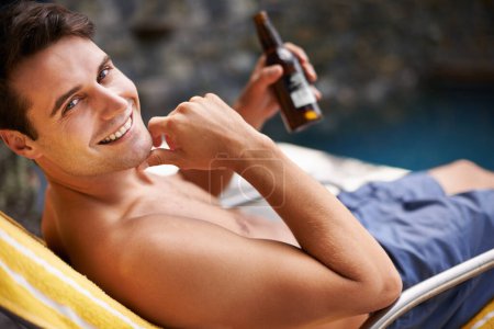 Téléchargez les photos : Portrait, homme et détente au bord de la piscine avec de la bière pour boire ou se détendre pendant les vacances d'été, luxe et station balnéaire ou villa. Homme, bouteille et alcool pour des rafraîchissements pendant les vacances tropicales aux Maldives - en image libre de droit