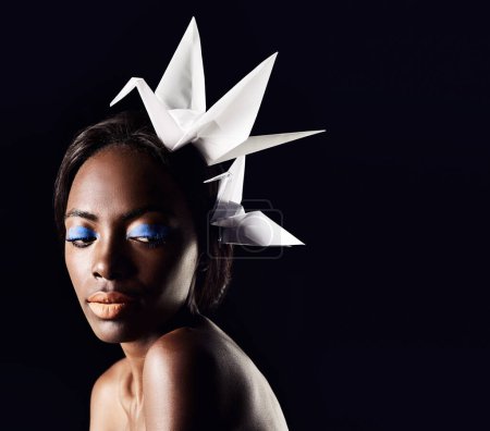 Téléchargez les photos : Studio, beauté et cosmétiques pour femme noire avec origami en fond sombre avec esthétique pour le luxe. Fard à paupières, lueur et fond de teint sur le visage de la fille pour briller, femme africaine et maquillage. - en image libre de droit