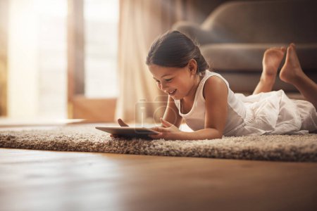 Photo for Girl, happy and playing with tablet on carpet for digital education, ebook and child development in house. German kid, smile and tech on floor for cartoon, video and movie or virtual gaming app. - Royalty Free Image