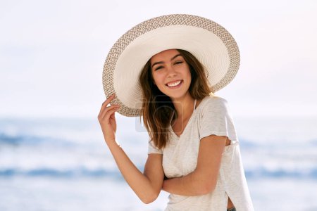 Téléchargez les photos : Portrait, sourire et femme avec chapeau de soleil à la plage pour les voyages d'été, les vacances et le tourisme à Miami. Plein air, heureux et détendez-vous au bord de l'océan avec paix pour l'aventure, week-end et confiance en vacances. - en image libre de droit
