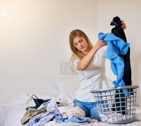 Photo for Tired, woman and cleaning laundry in home and frustrated with dirty clothes in basket on bed, Girl, washing and cleaner start task in apartment with chaos of linen, fabric and mess in bedroom to tidy. - Royalty Free Image