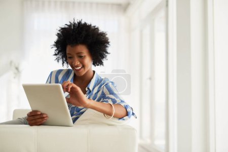 Black woman, home and happy sofa with tablet for social media post and entertainment. Female person, living room and couch on internet for streaming service or website for news update or funny videos.